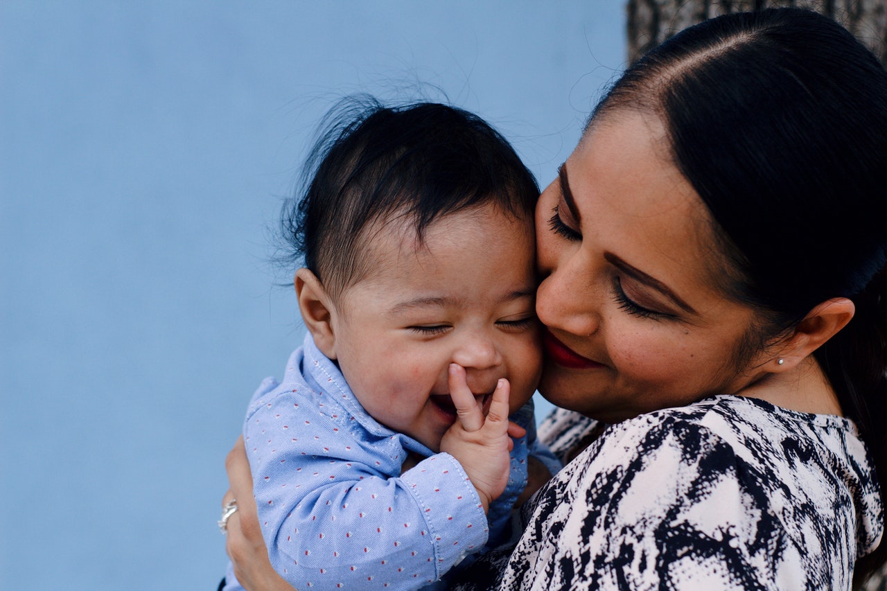 close-up-photo-of-smiling-woman-carrying-her-smiling-baby-3766464