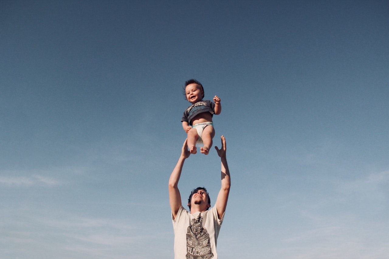 photo-of-man-in-raising-baby-under-blue-sky-1166990